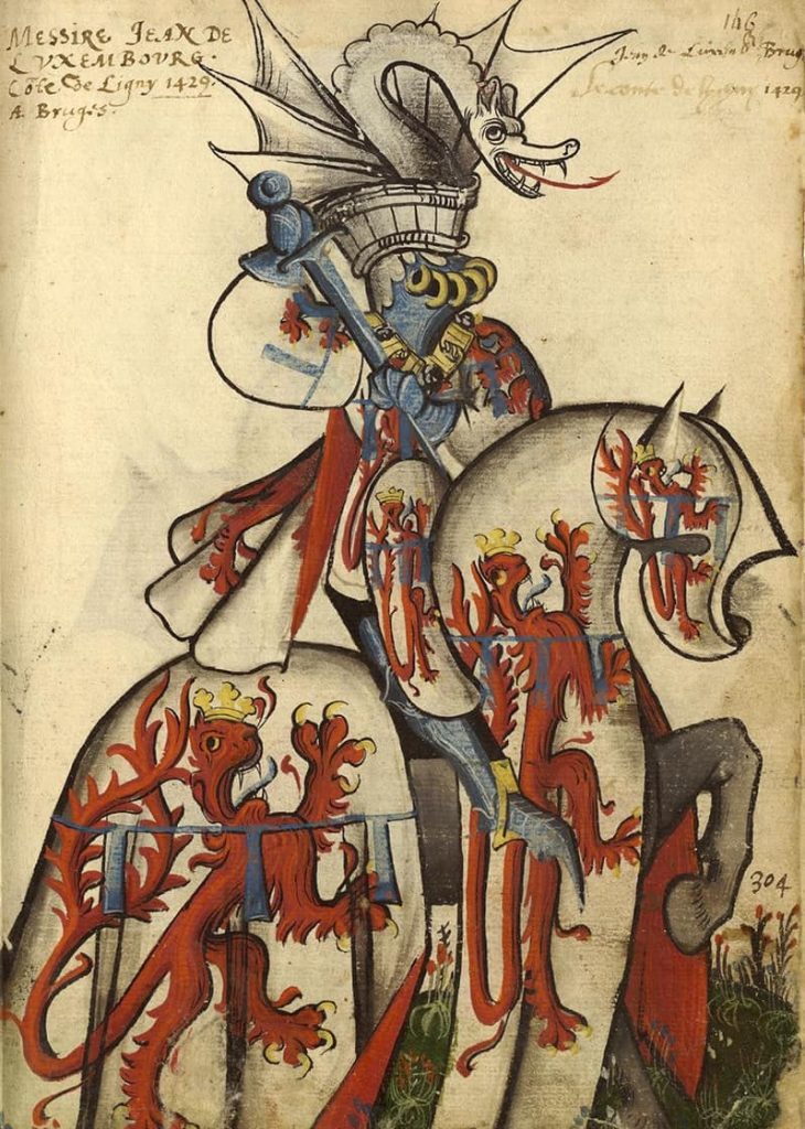 Jean de Luxembourg, comte de Ligny, chevalier de la Toison d'or (première promotion, 1430). Armoiries d'argent au lion de gueules couronné d'or, la queue fourchée et passée en sautoir, au lambel d'azur. Devise : « Vostre vueil ». Grand Armorial équestre de la Toison d'Or, Flandre, v. 1430-1461. BnF, Bibliothèque de l'Arsenal, Ms. 4790, f. 146.